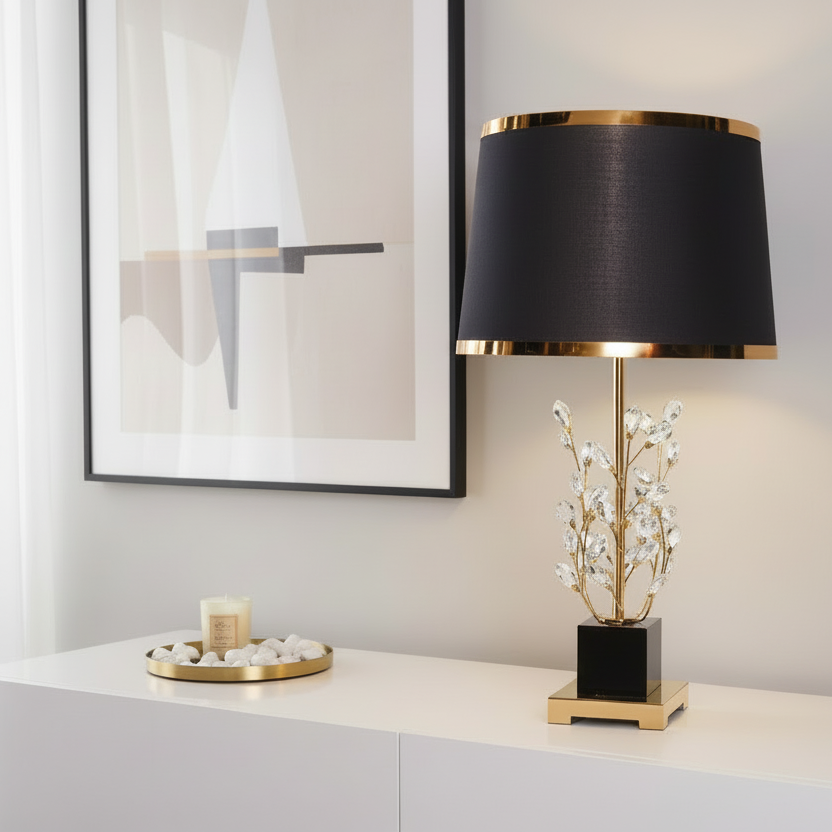 Decorative table lamp with black shade and gold base on a white surface.