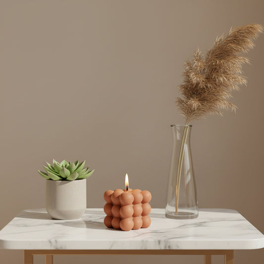 Two egg-shaped candle holders on a table with plants in the background