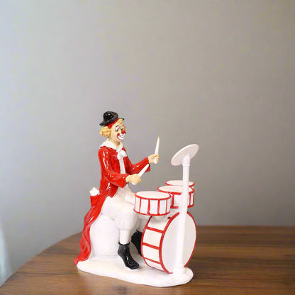 Clown figurine playing drums on a plain background