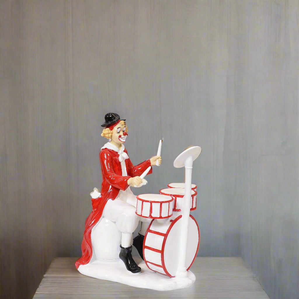 Clown figurine playing drums on a gray background