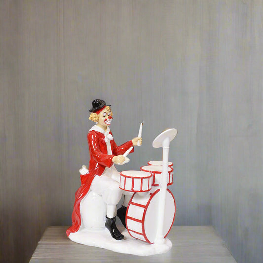 Clown figurine playing drums on a gray background