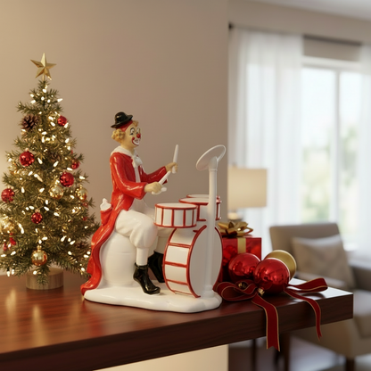Decorative clown figurine with drums on a table next to a Christmas tree.