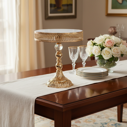 Dining table set with a white tablecloth, gold candle holder, wine glasses, and flowers in a room.