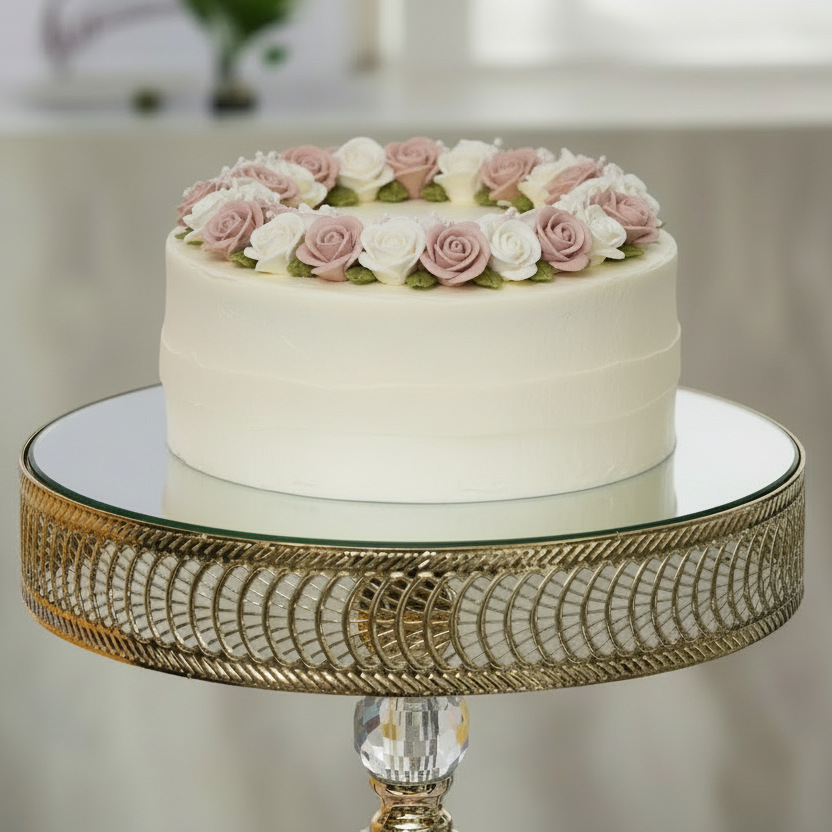 White cake with pink and white flowers on a decorative stand with a blurred background
