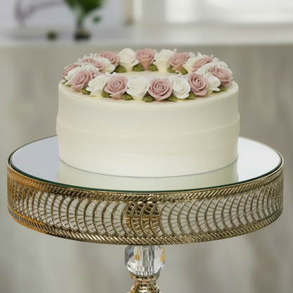 White cake with pink and white flowers on a decorative stand with a blurred background
