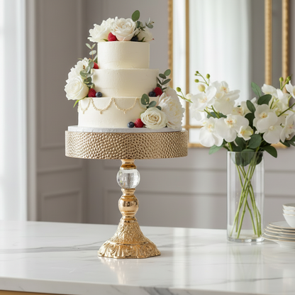 Decorative cake stand with a cake and flowers on a marble surface.