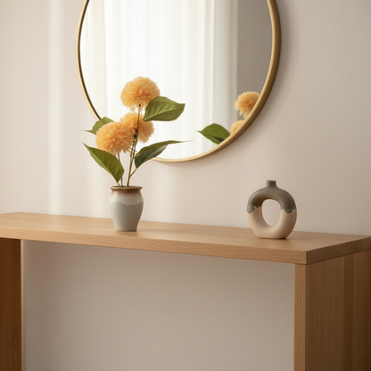 Decorative setup with a round mirror, vase with flowers, and another vase on a wooden surface.