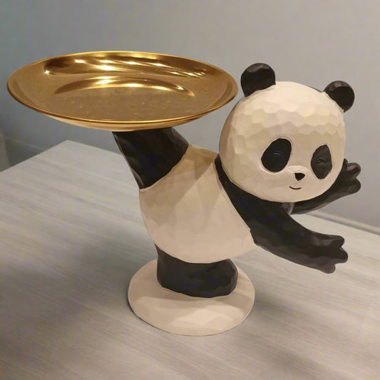 Panda-shaped object holding a gold plate on a neutral background