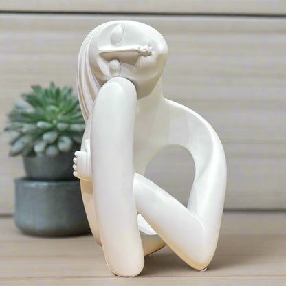 White abstract sculpture on a wooden surface with a green background