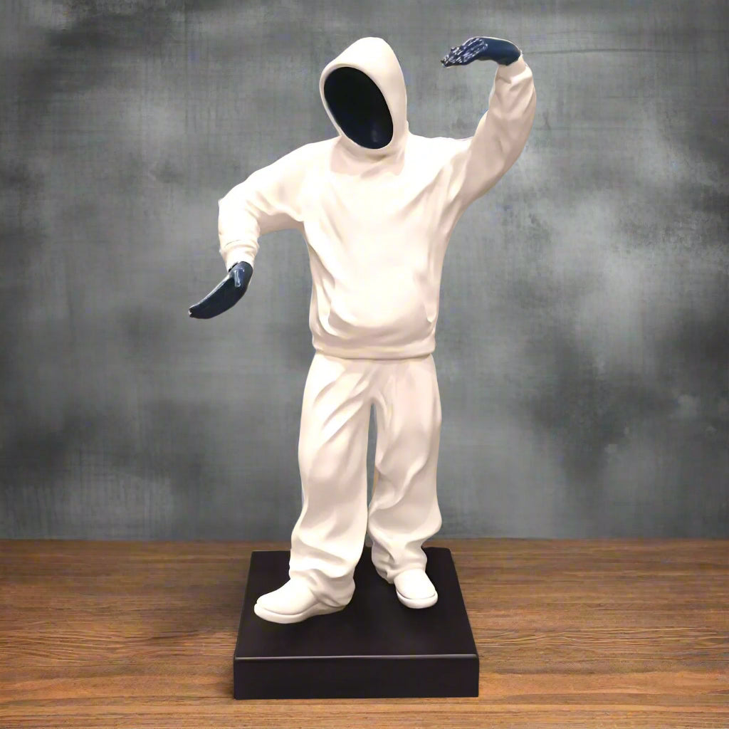 Statue of a person in a white outfit with black gloves on a wooden surface and gray background