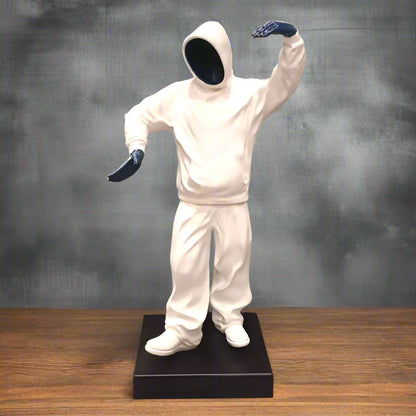 Statue of a person in a white outfit with black gloves on a wooden surface and gray background