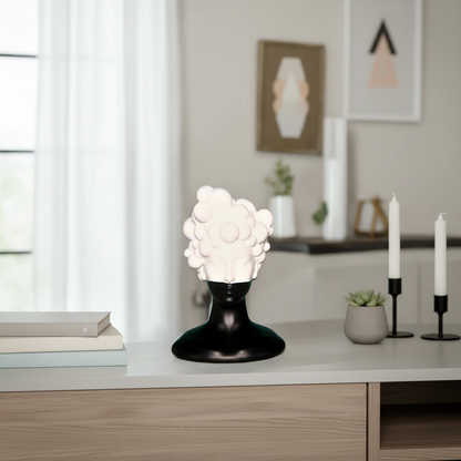 Decorative lamp with white textured shade and black base on a shelf in a room.