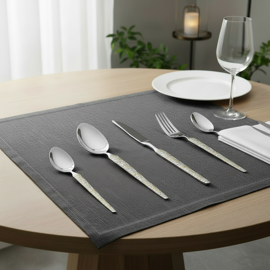 Dining table setting with silverware, plates, and a glass on a gray placemat.