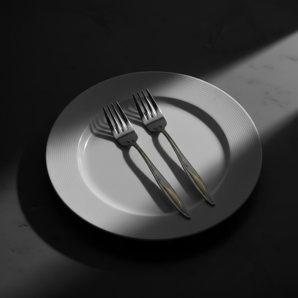 Two silver forks resting on a white plate with concentric ridges, set on a dark surface under dramatic spotlighting.