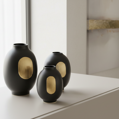 Three black vases with gold accents on a wooden surface