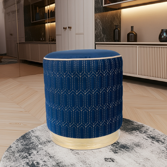 Blue quilted ottoman with a gold band on a white background