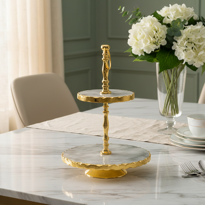 Gold cake stand on a marble table with white flowers in the background