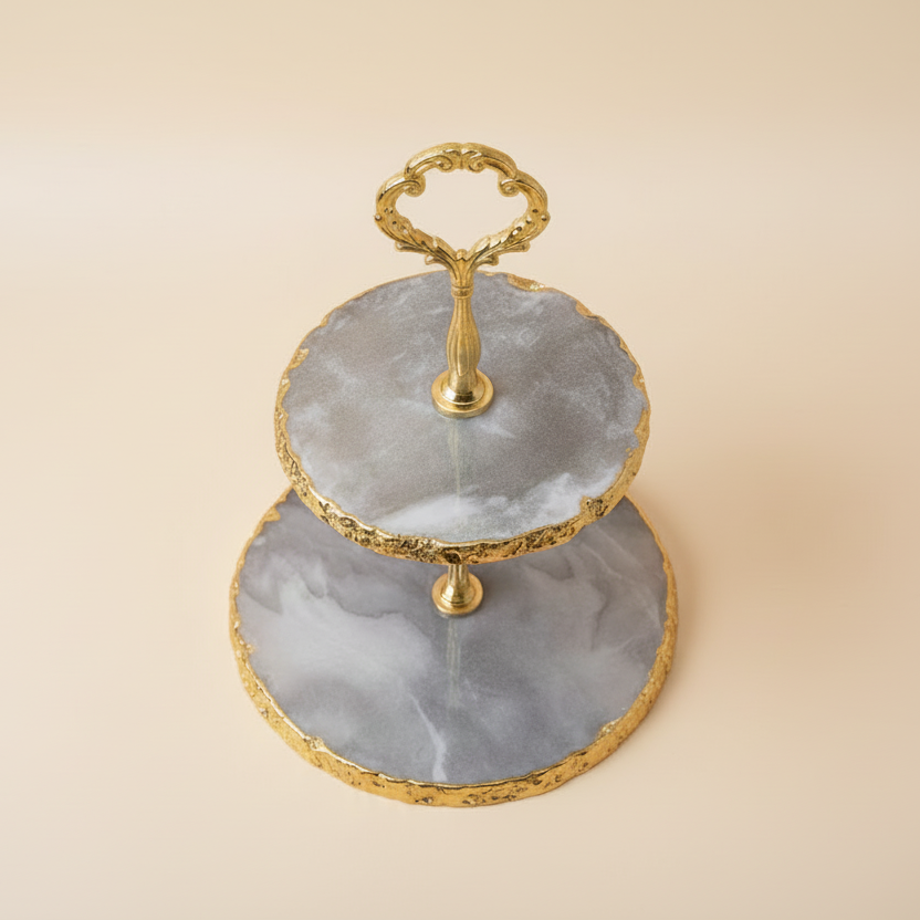 Two-tiered serving tray with gold accents on a beige background