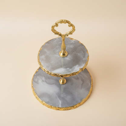 Two-tiered serving tray with gold accents on a beige background