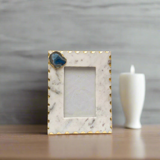 Marble picture frame with gold accents and a blue stone on a white background