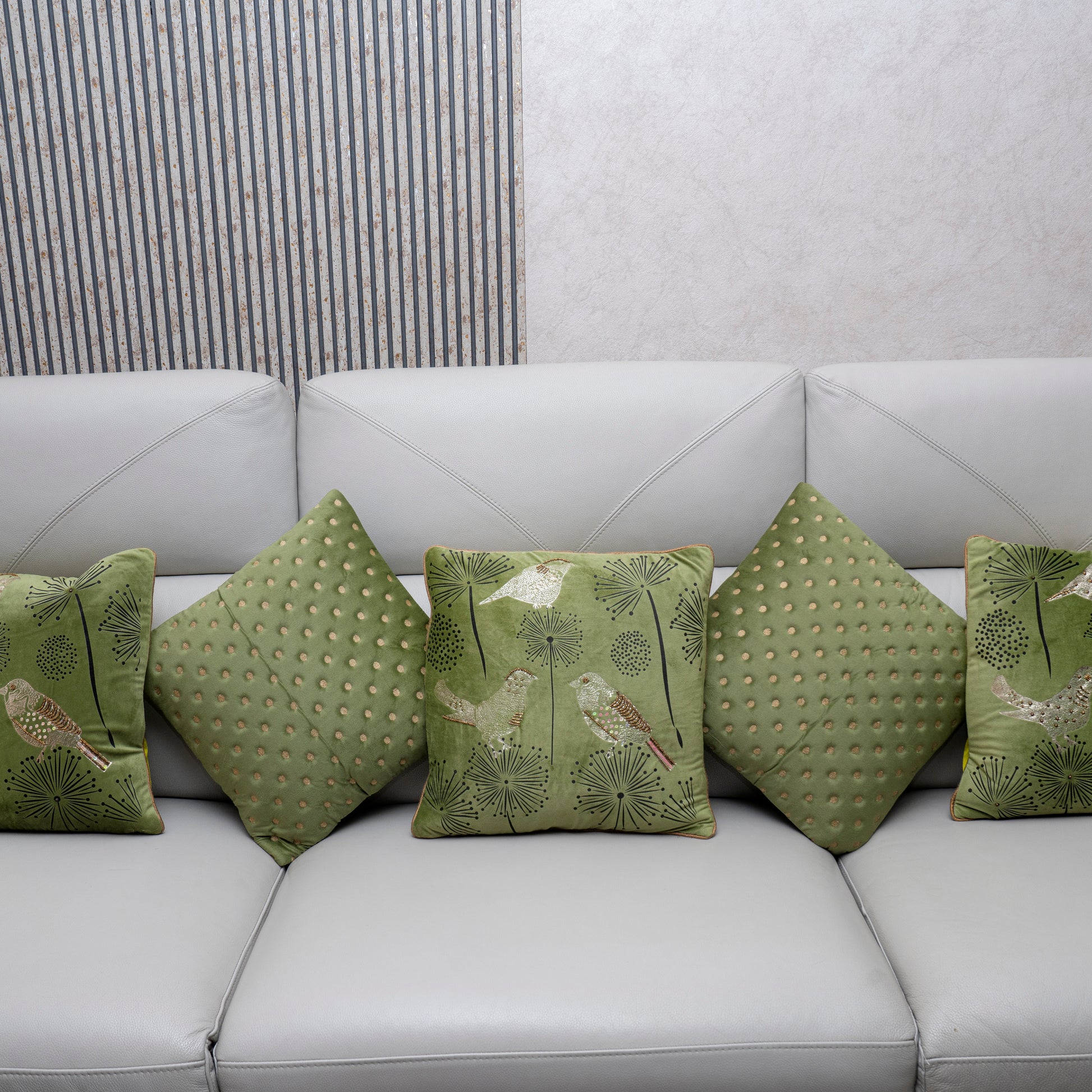 Green patterned cushions on a white sofa against a neutral wall.
