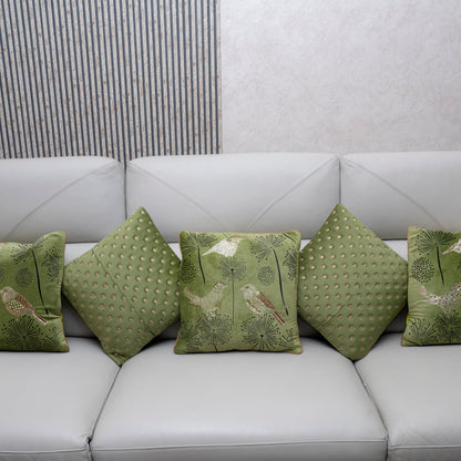 Green patterned cushions on a white sofa against a neutral wall.
