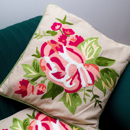 Floral embroidered pillow on a dark green cushion with a gray background