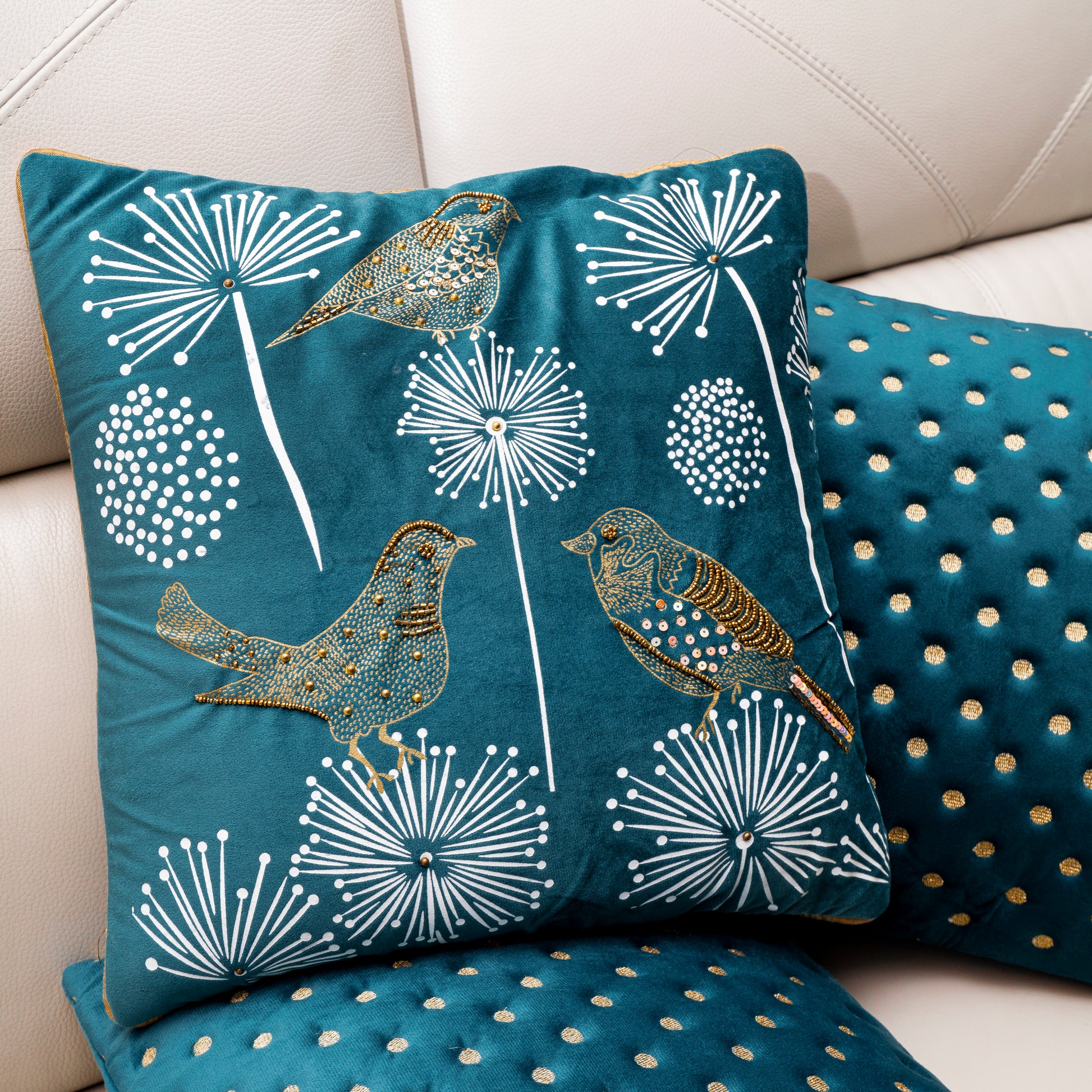 Decorative pillows with bird and dandelion design on a white sofa.