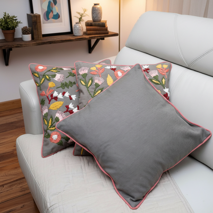 Gray cushions with floral patterns on a white sofa in a living room setting.