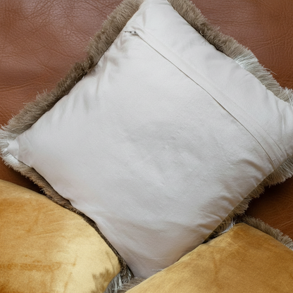 White pillow with brown trim on a brown leather couch