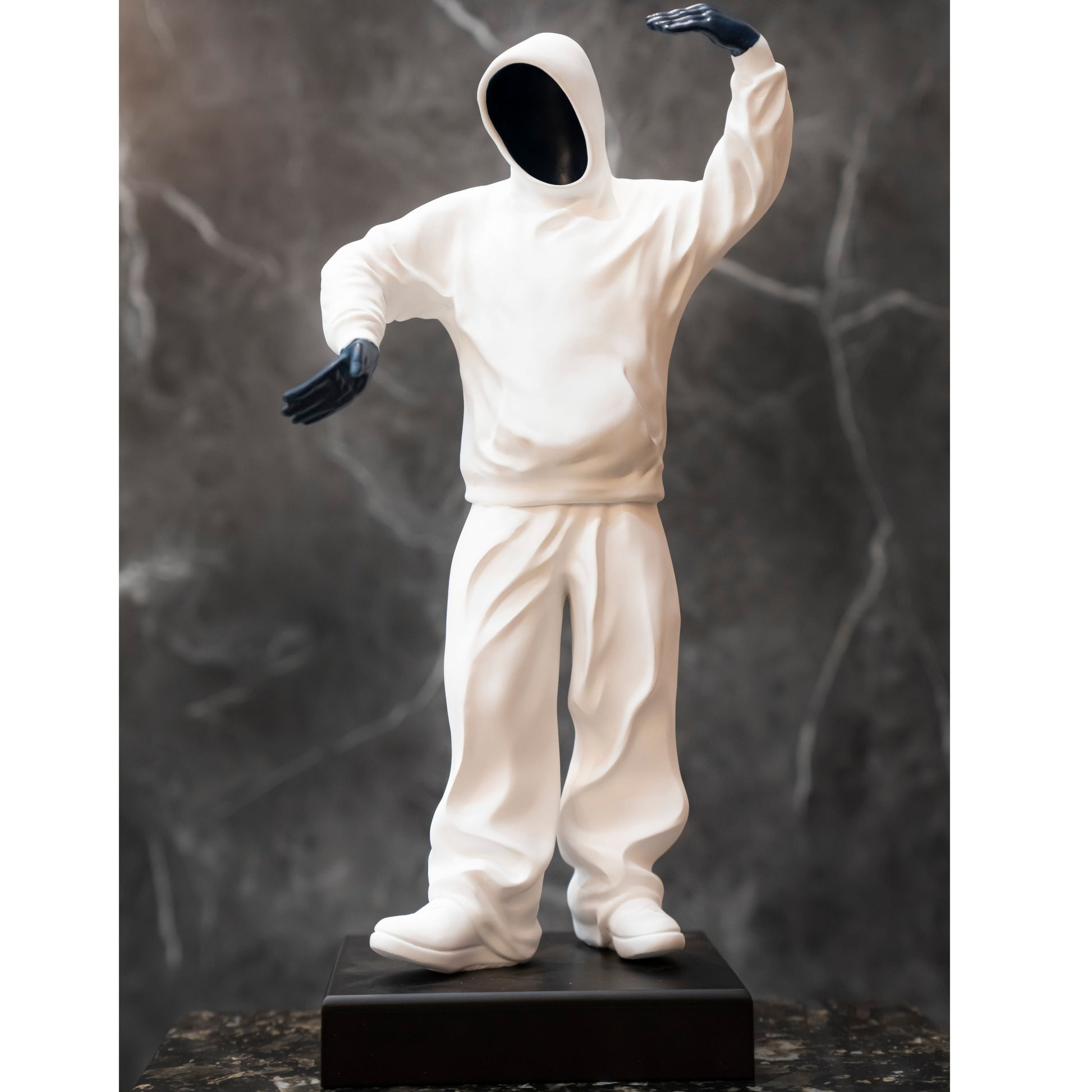 Statue of a person in a white outfit with black gloves against a dark marble background