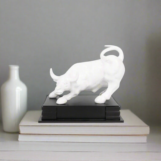 White bull sculpture on a black base against a white background