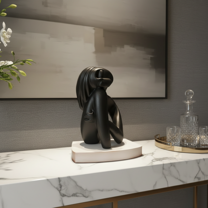 Black abstract sculpture on a marble surface with a neutral background