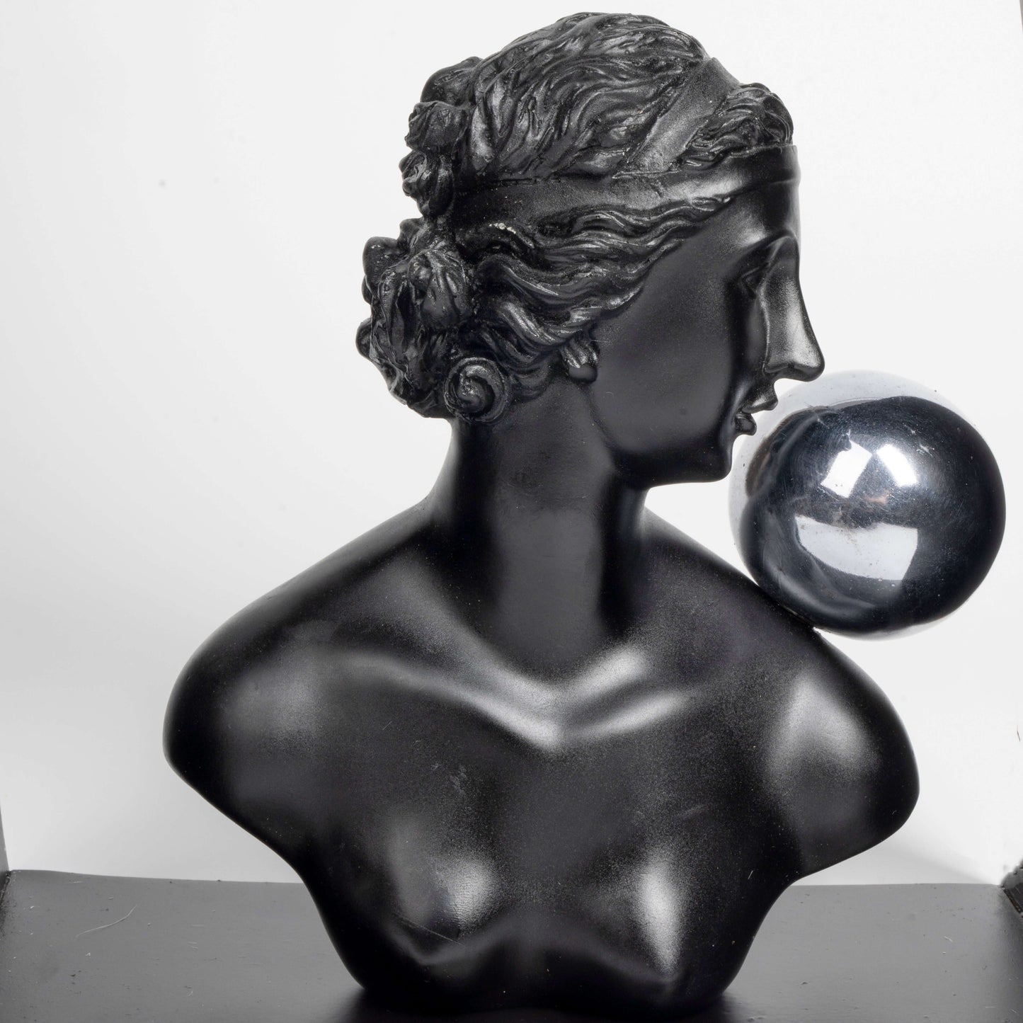 Black marble bust of a woman with a crystal ball on a white background