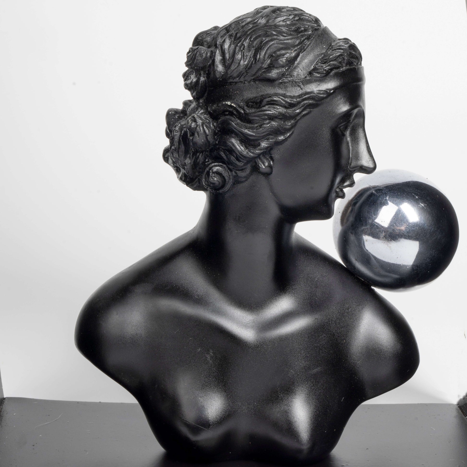 Black marble bust of a woman with a crystal ball on a white background