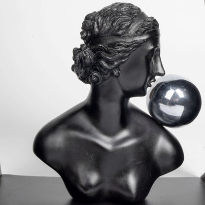 Black marble bust of a woman with a crystal ball on a white background