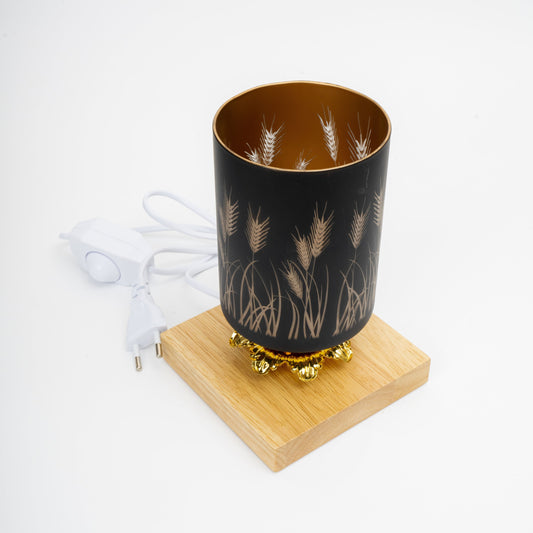 Black lampshade with gold leaf design on a wooden base with white cord