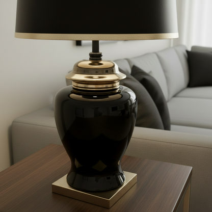 Black table lamp with gold base on a wooden side table in a living room setting.