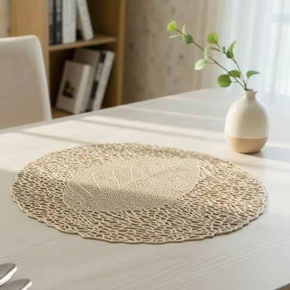 Round woven placemat on a table with a vase and plant in the background