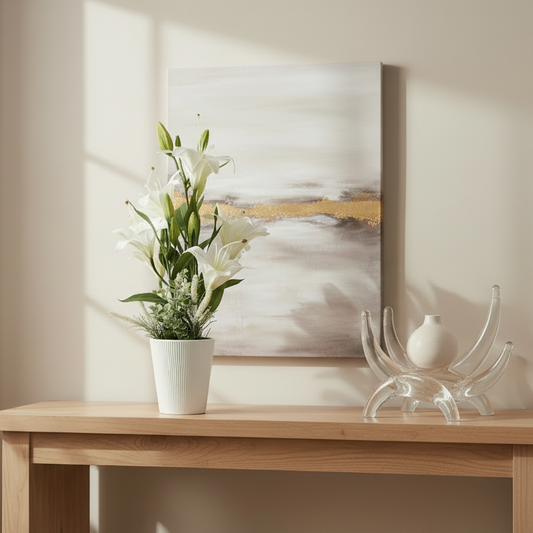 Wooden console table with a potted plant and decorative items against a wall with a painting.