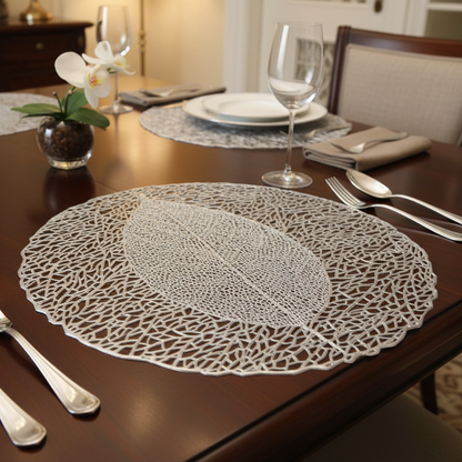 Dining table set with lace placemats, silverware, and a vase with an orchid.