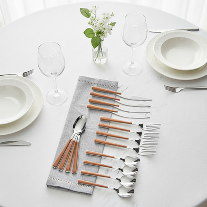 Set of silver and brown cutlery on a white table with plates and glasses.