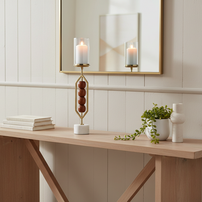 Decorative candle holder with a candle on a marble surface against a neutral wall.