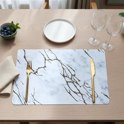 Dining table setting with marble placemat, gold fork and knife, and white plate.