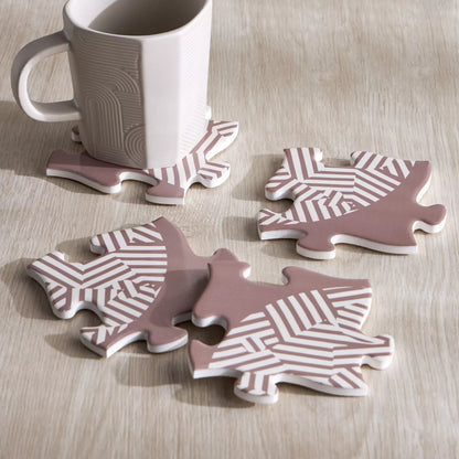 Set of four pink and white patterned coasters on a wooden surface with a mug.