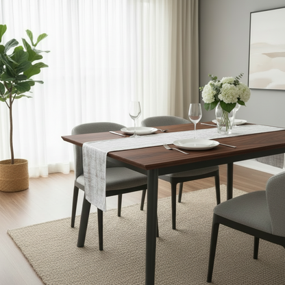 Dining room with a wooden table set for four, chairs, and a plant.