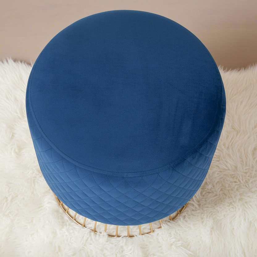 Blue ottoman with quilted design on a white fluffy surface