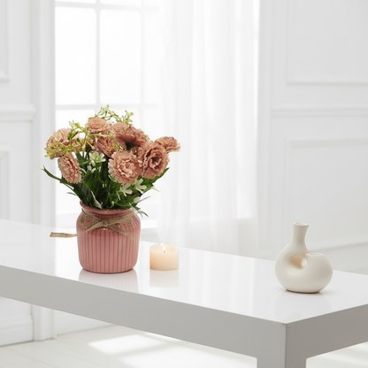 Pink vase with flowers and a candle on a gray background