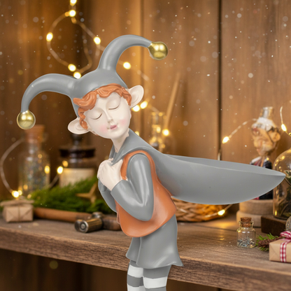 Elf figurine with a jester hat on a wooden surface with decorative lights in the background