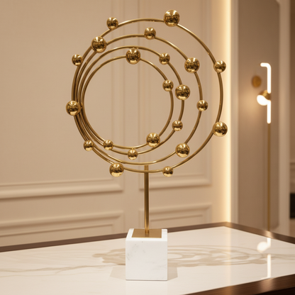 Decorative gold sculpture on a white base against a neutral wall.